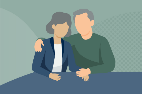 A older couple holding hands, sitting at table