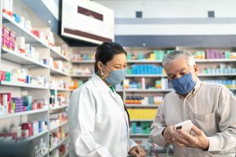 Older Adults' Experiences with Comprehensive Medication Reviews patient wearing mask showing medication to pharamacist wearing mask