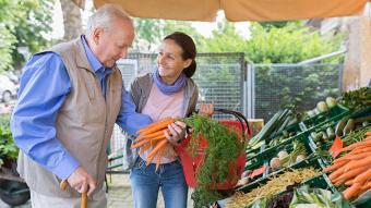 Older adults at a farmer's market with a helper