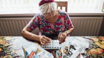 An older woman sitting at kitchen table sorting her medication
