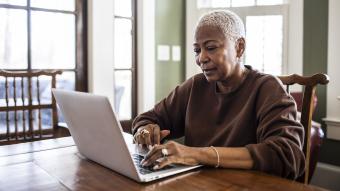 older woman on laptop at dining table