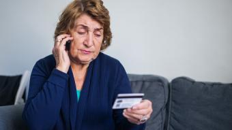 An older woman on phone holding a credit card