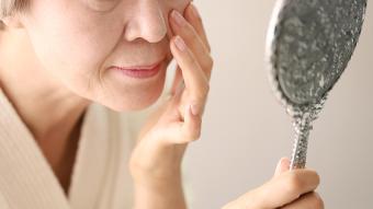 Senior woman checking face in mirror