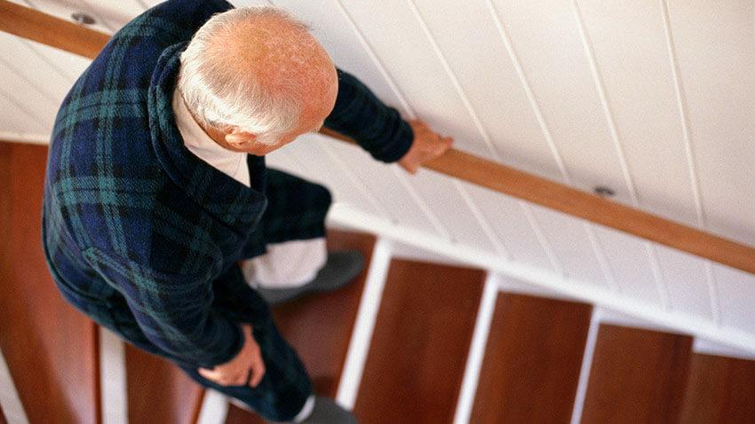 Older man bending on stairs in pain